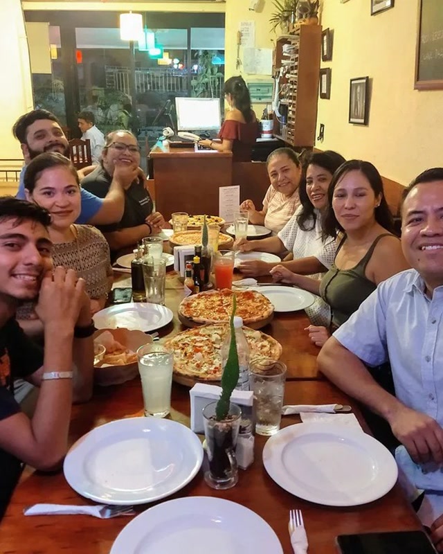 Mesa larga con familia y amigos compartiendo pizzas en Mr. Lasaña, Cancún